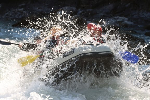 Descentes en rafting sur une rivière tumultueuse avec des éclaboussures d'eau.