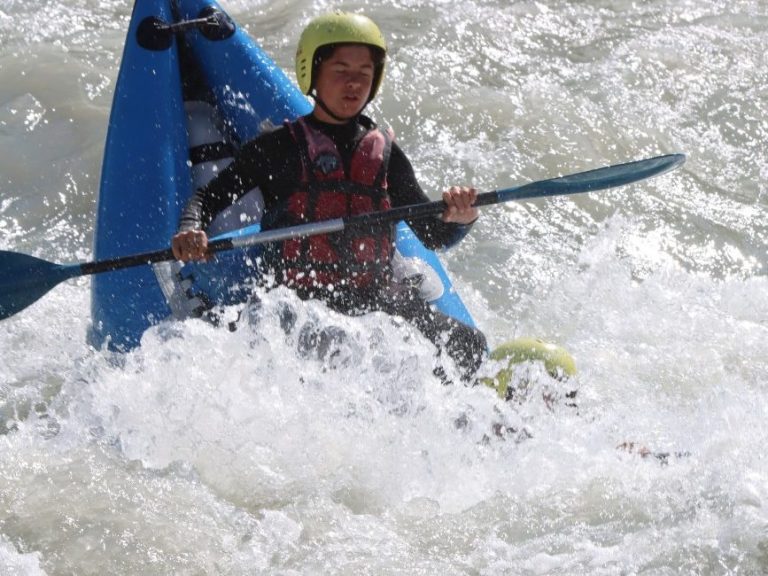 Person en kayak naviguant dans des eaux vives, éclaboussures autour d'eux.