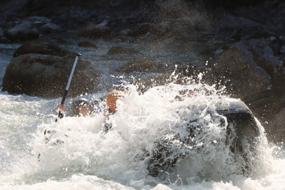 Descent en radeau dans des rapides avec des éclaboussures d'eau.